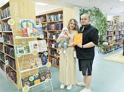родители с младенцем стоят у книжной выставки