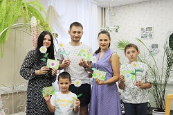 семья из пяти человек в руках держат ромашки из бумаги